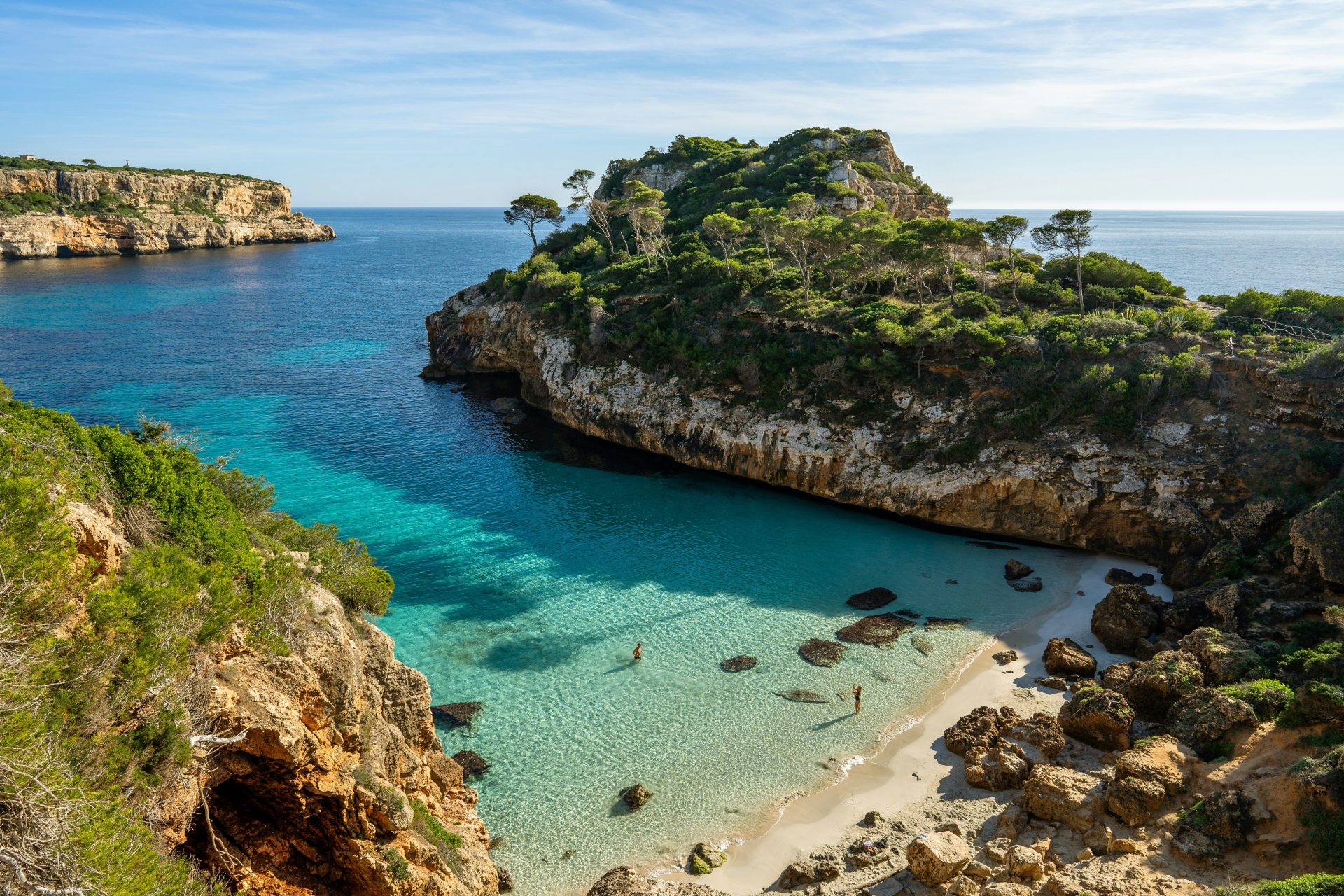 a beach with clear blue water next to a cliff